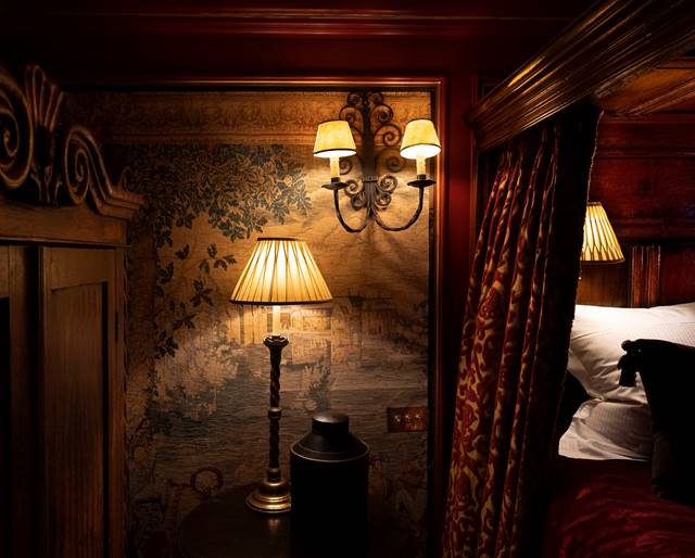 Antique lamp, wall panels and gothic velvet drapery on four poster bed in The Armoury hotel suite, in Edinburgh UK