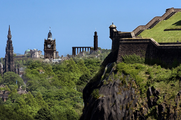 View of Calton Hill in Edinburgh with its iconic monuments, set against a backdrop of blue sky in summer