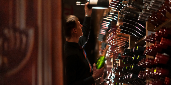 Wine racks and sommelier holding a bottle in the cellar at the Best Edinburgh restaurant for fine wines 