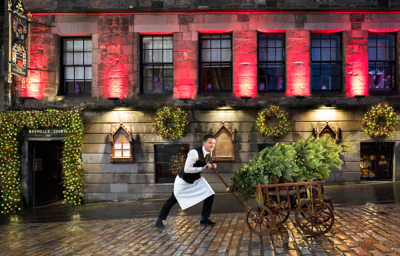 Man pushing wooden cart with a Christmas Tree outside The Witchery